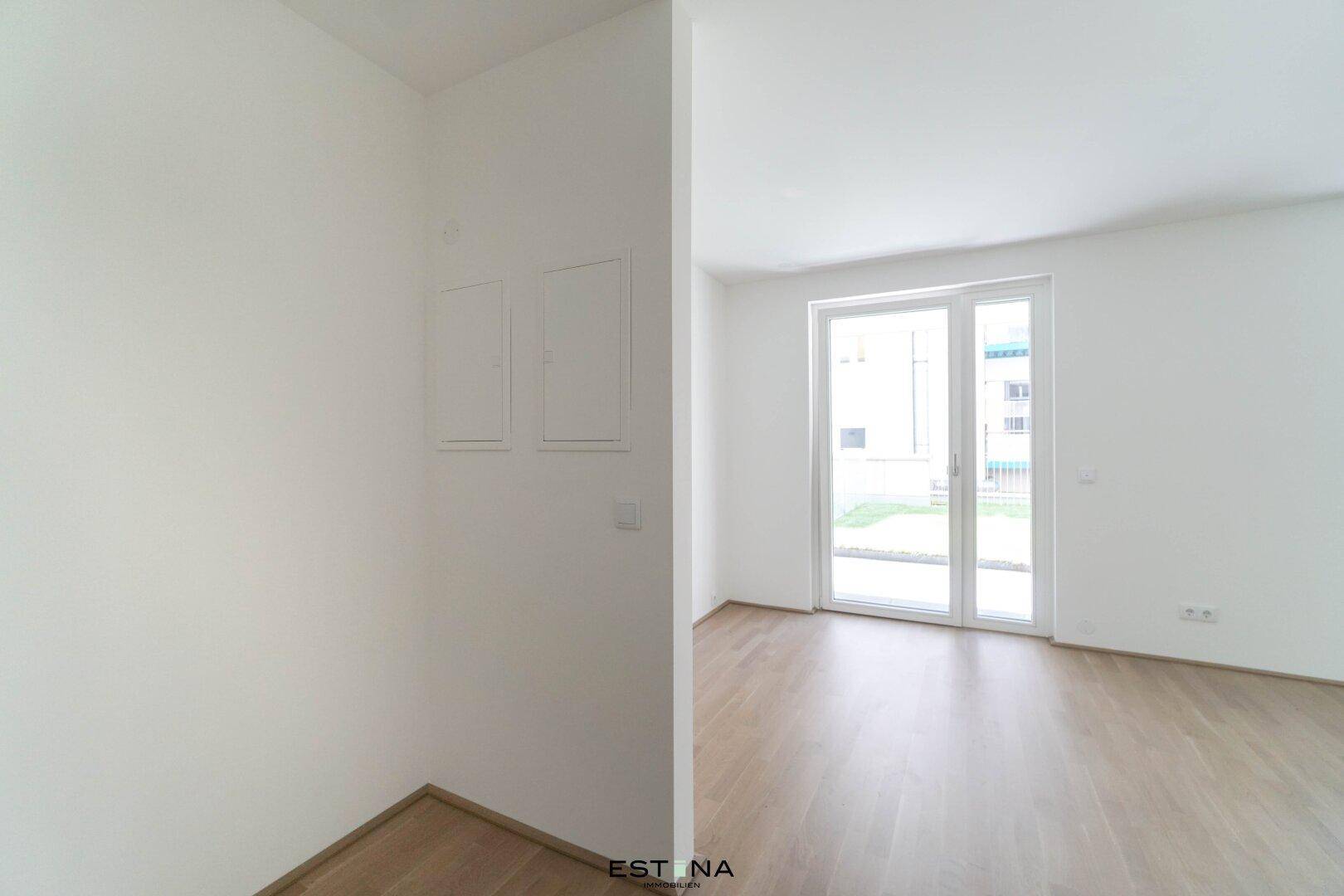 Heller Wohnraum mit Zugang zu einem Außenbereich und modernem Parkettboden.