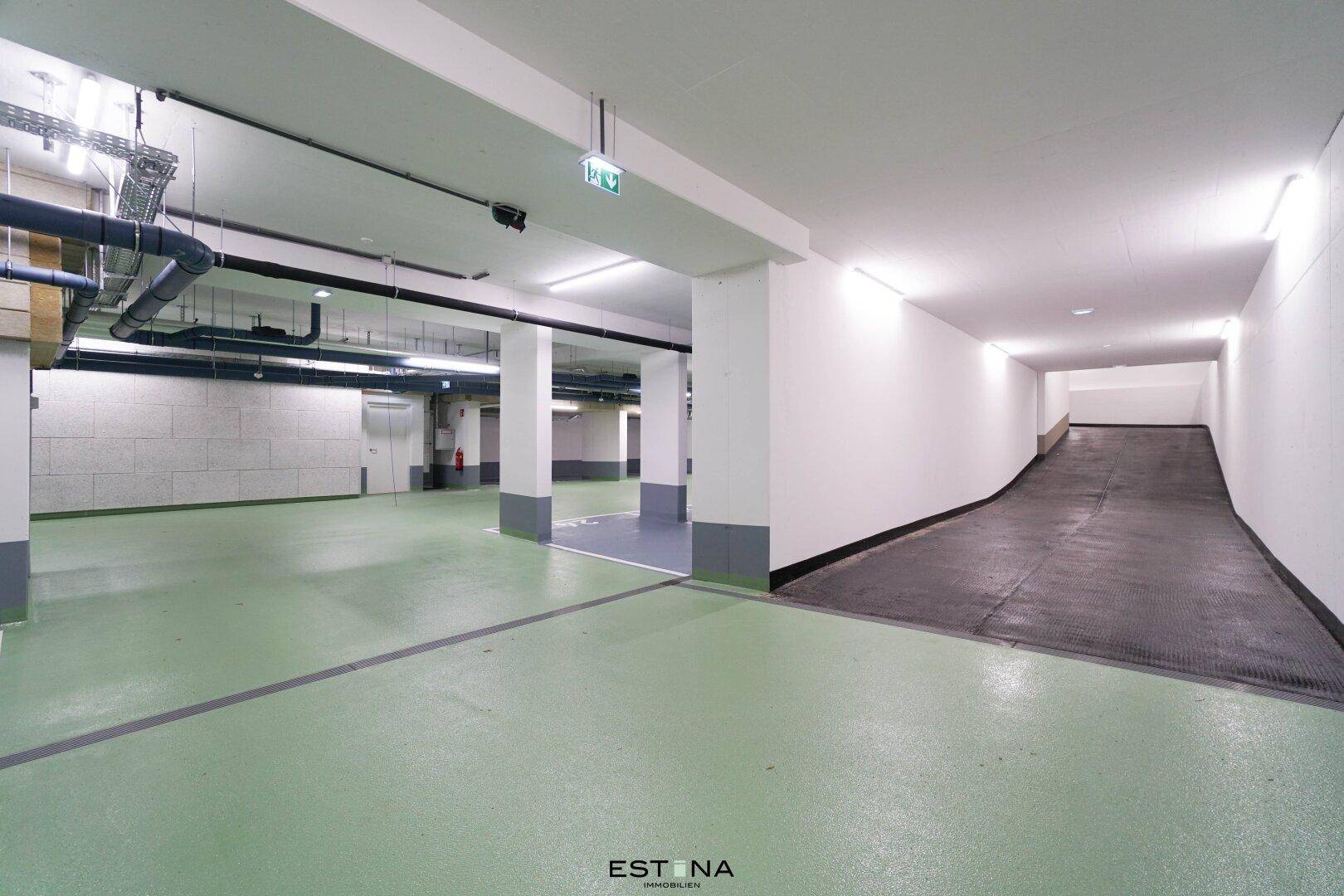 Einfahrt zur Tiefgarage mit breiter Rampe und guter Beleuchtung.