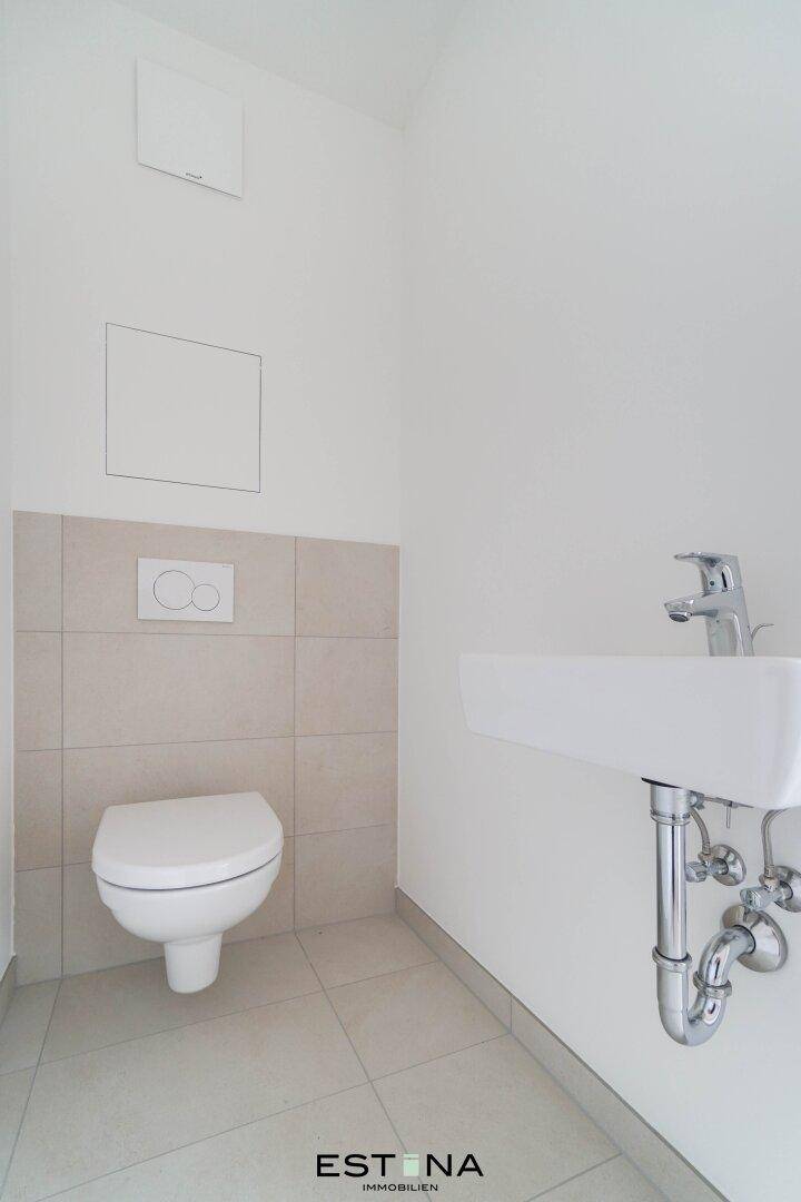 Modernes Gäste-WC mit wandhängender Toilette und kleinem Waschbecken.