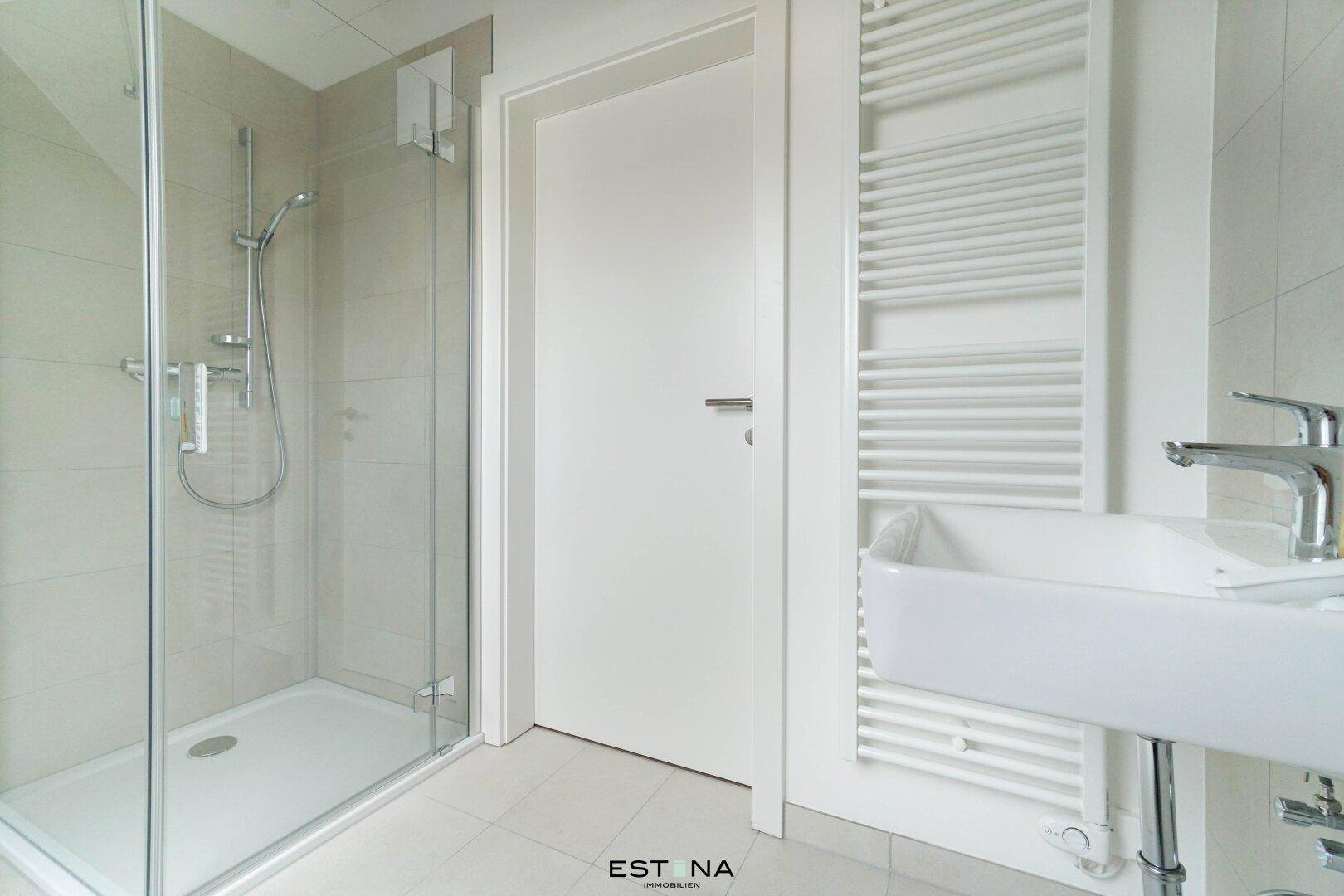 Modernes Badezimmer mit ebenerdiger Dusche, Einzelwaschbecken und beheiztem Handtuchhalter.