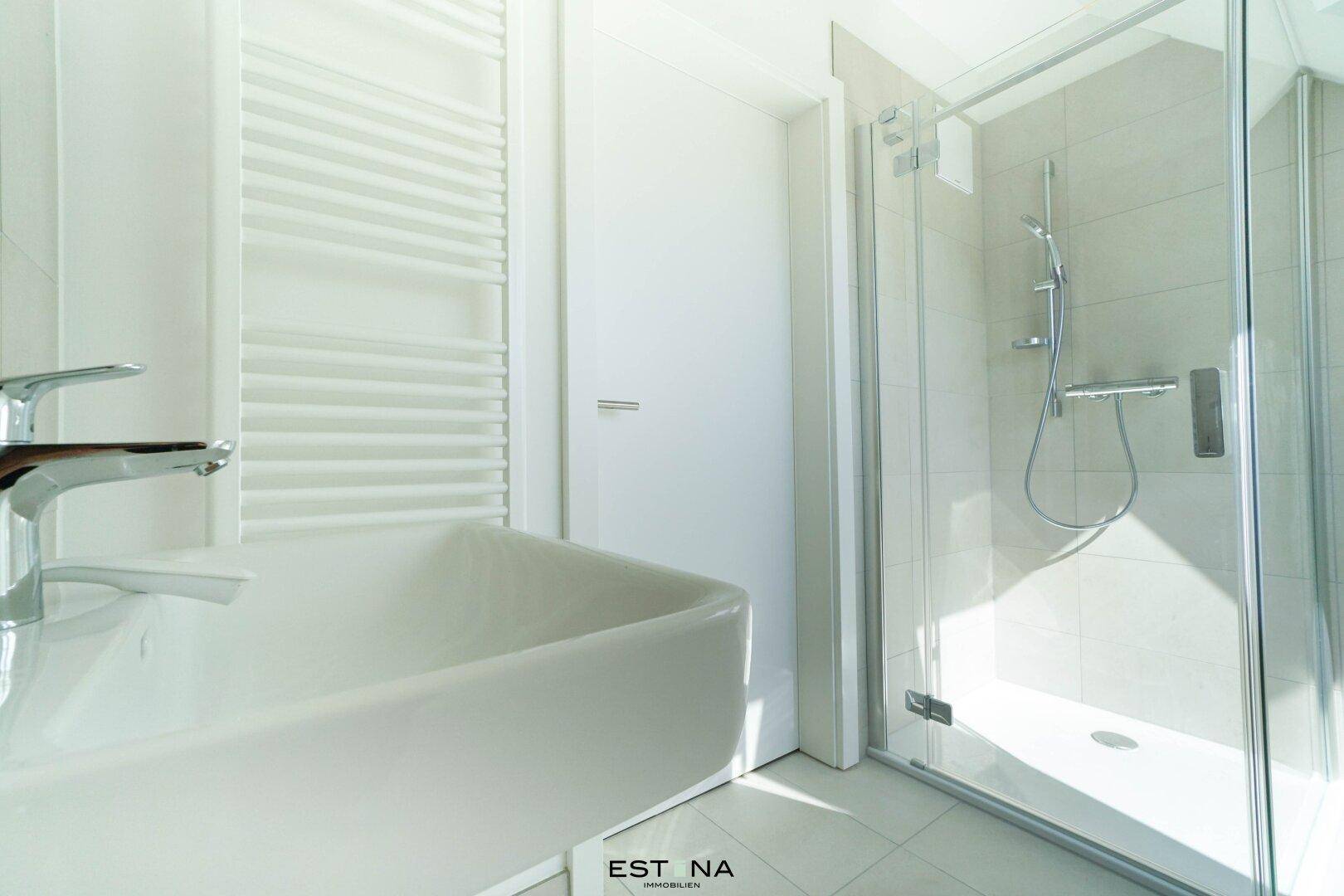 Modernes Badezimmer mit weißem Waschbecken, Handtuchheizkörper und Duschkabine.
