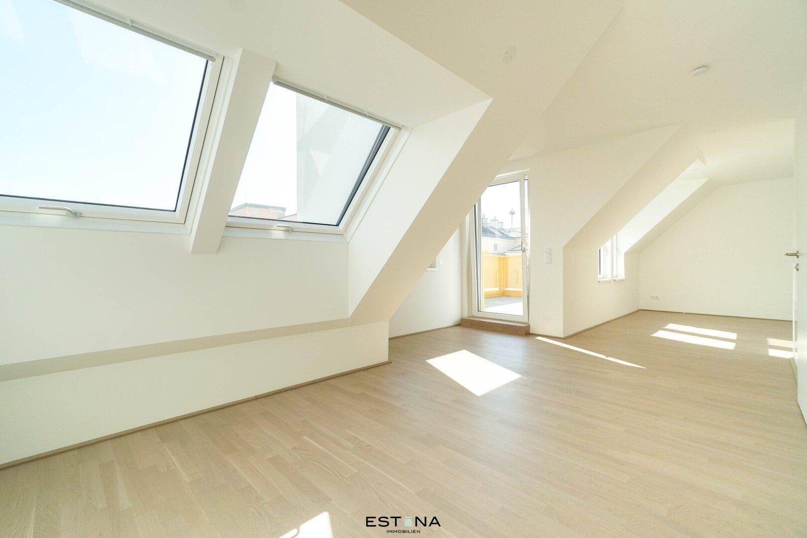Heller, unmöblierter Raum in Dachgeschosswohnung mit Holzboden und Zugang zu einem Balkon.