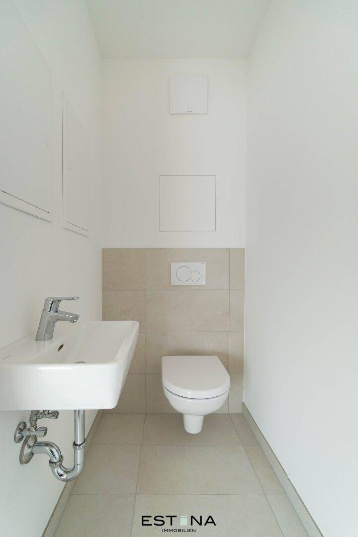 Modernes Gäste-WC mit wandhängender Toilette und kleinem Waschbecken.