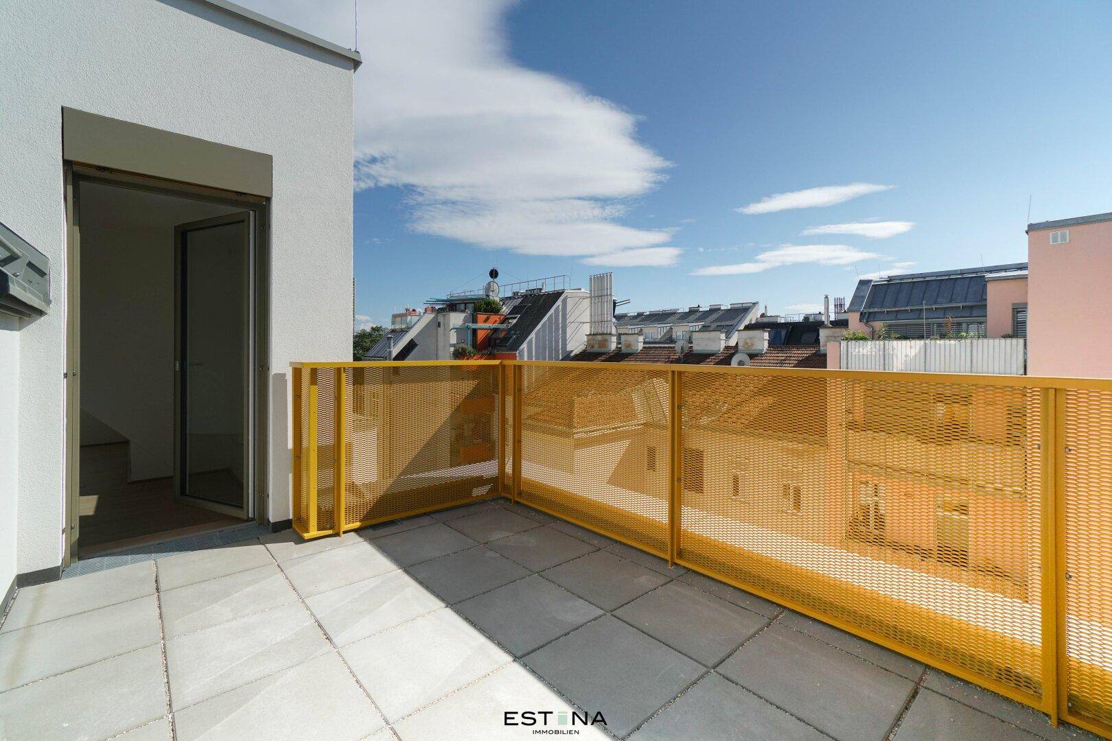 Heller Balkon mit gelbem Gittergeländer und Zugang zum Innenbereich der Wohnung.