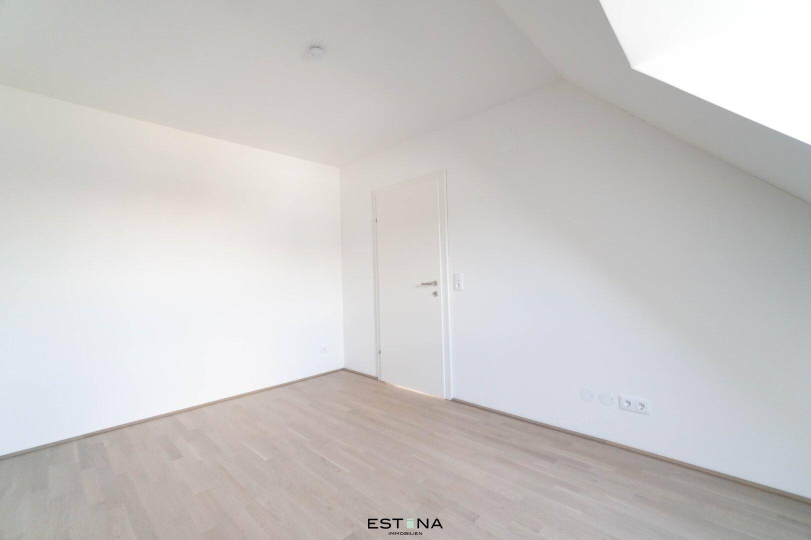 Ruhiges Schlafzimmer mit schrägen Wänden und hellem Parkettboden, ideal für eine gemütliche Einrichtung.