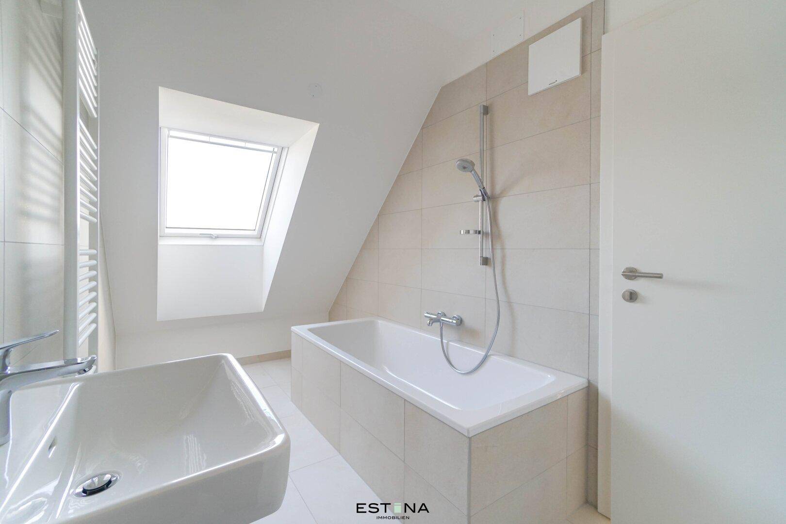 Modernes Badezimmer mit Badewanne, Waschbecken, Fliesen und einem praktischen Dachfenster.