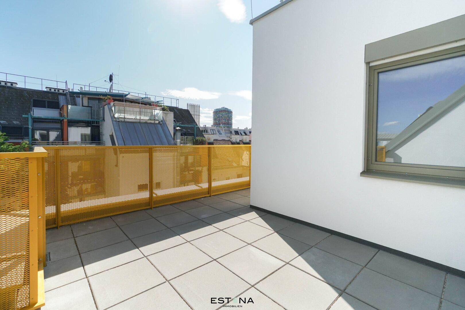 Sonnenterrasse mit modernen Fliesen und gelbem Geländer, bietet einen Blick auf die umliegenden Gebäude.