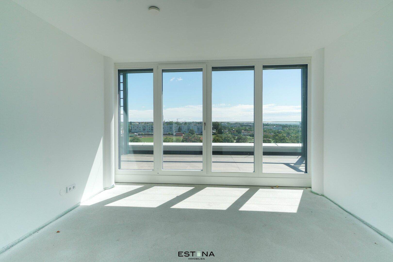 Lichtdurchflutetes Zimmer mit breiter Fensterfront und Blick auf die umliegende Landschaft.