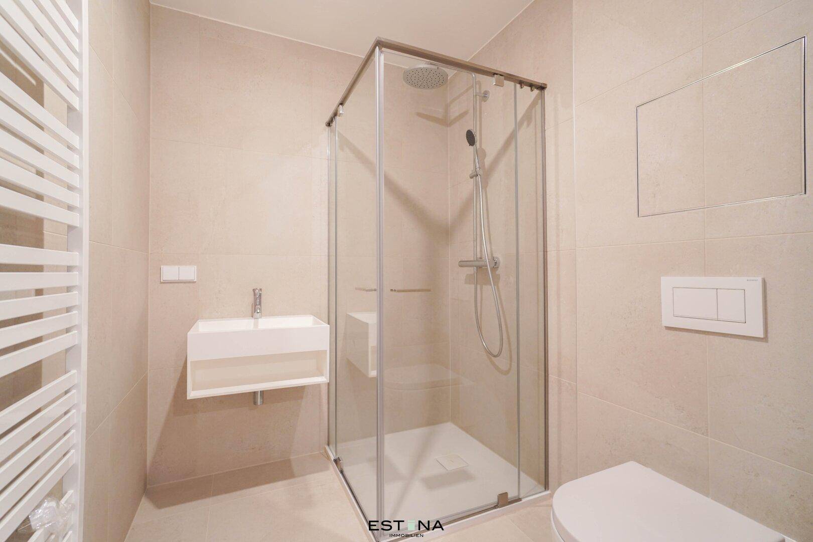 Modernes Badezimmer mit beigefarbenen Fliesen, einer begehbaren Dusche und einem beheizten Handtuchhalter.