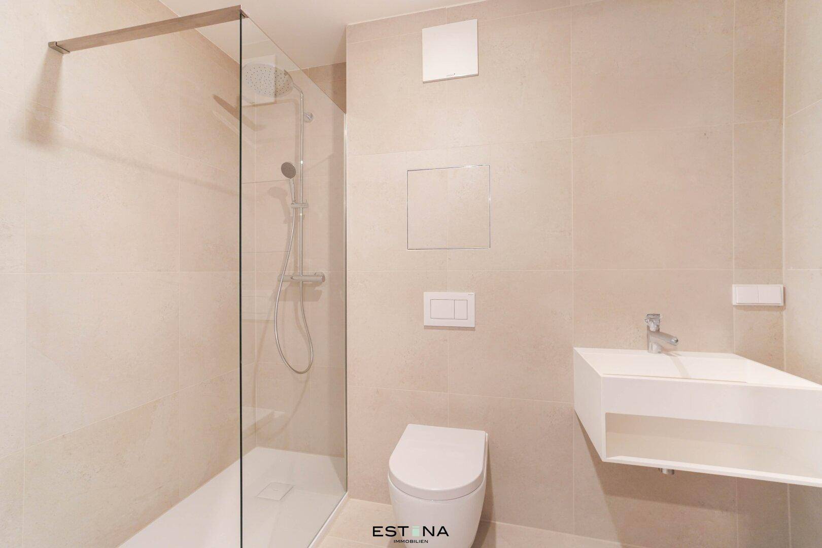 Modernes Badezimmer mit beigefarbenen Fliesen, wandhängendem WC und einer geräumigen begehbaren Dusche.