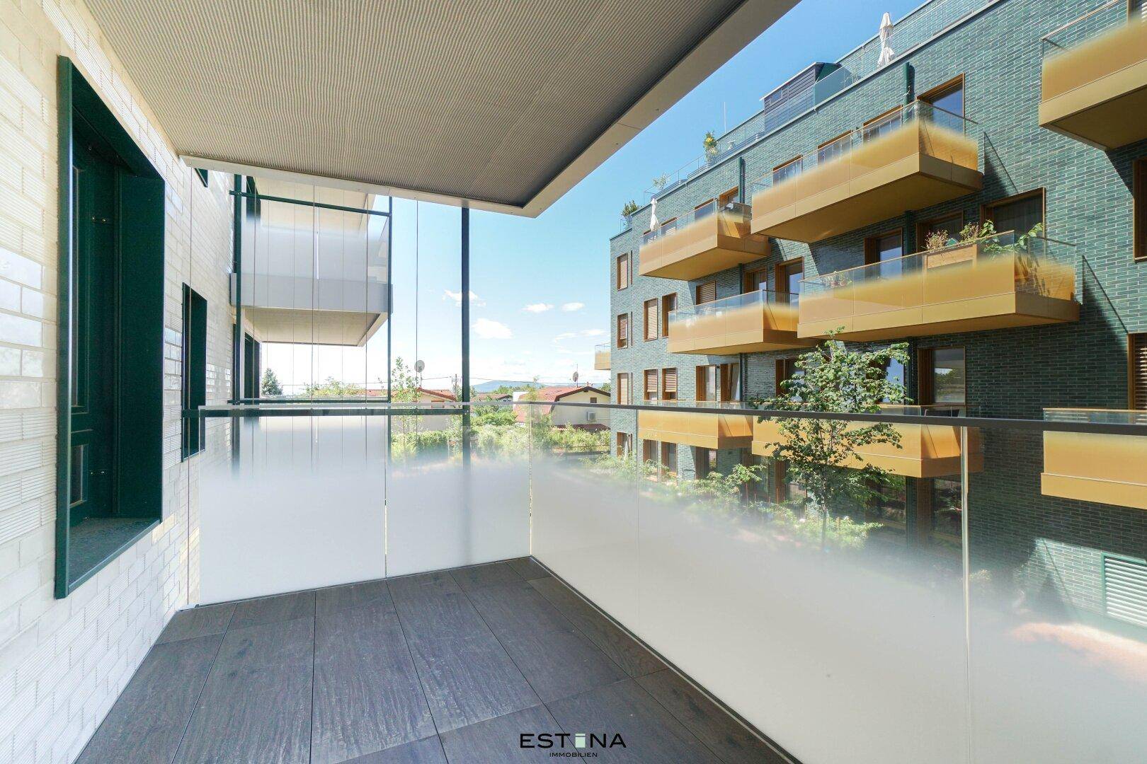Moderner Balkon mit Milchglasbrüstung und Blick auf ein zeitgenössisches Wohngebäude.
