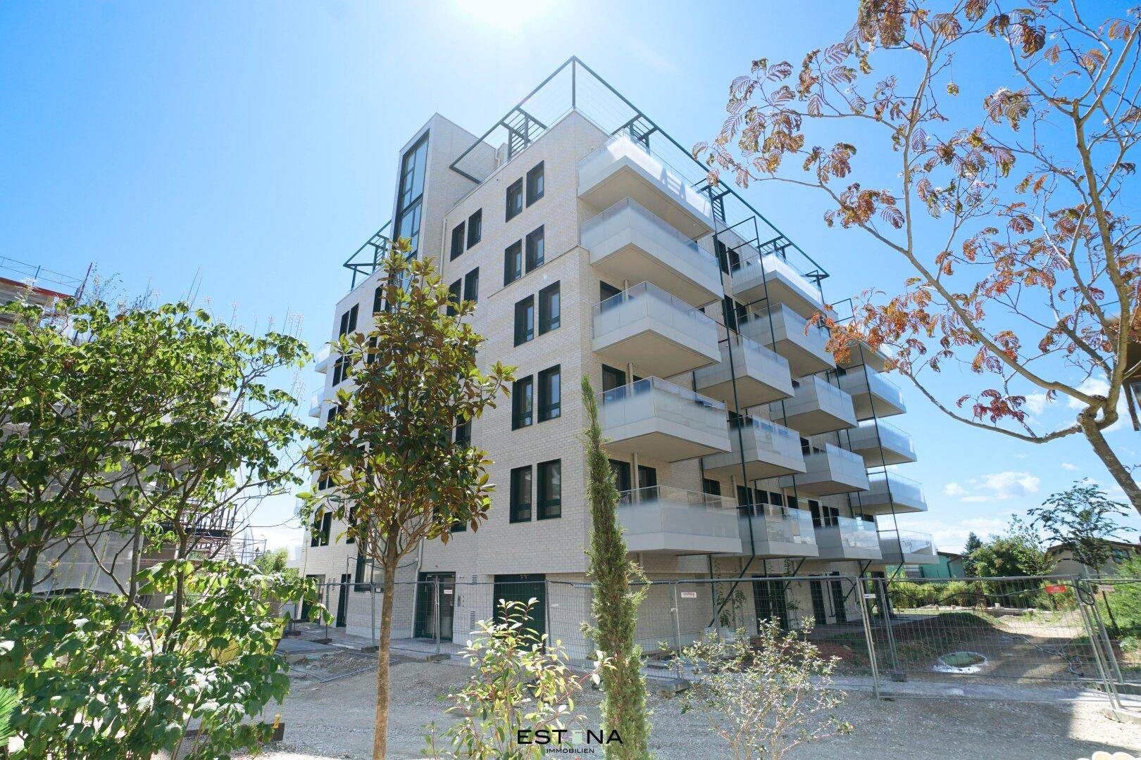 Modernes Mehrfamilienhaus mit zahlreichen Balkonen und zeitgenössischer Architektur unter blauem Himmel.