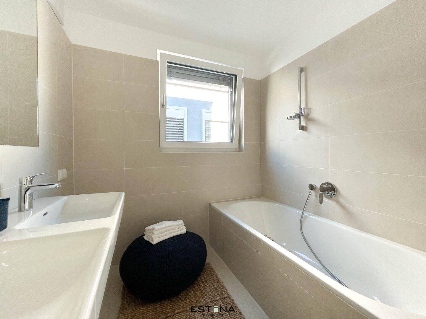 Modernes Badezimmer mit Badewanne, Einzelwaschbecken und beigefarbenen Fliesen.