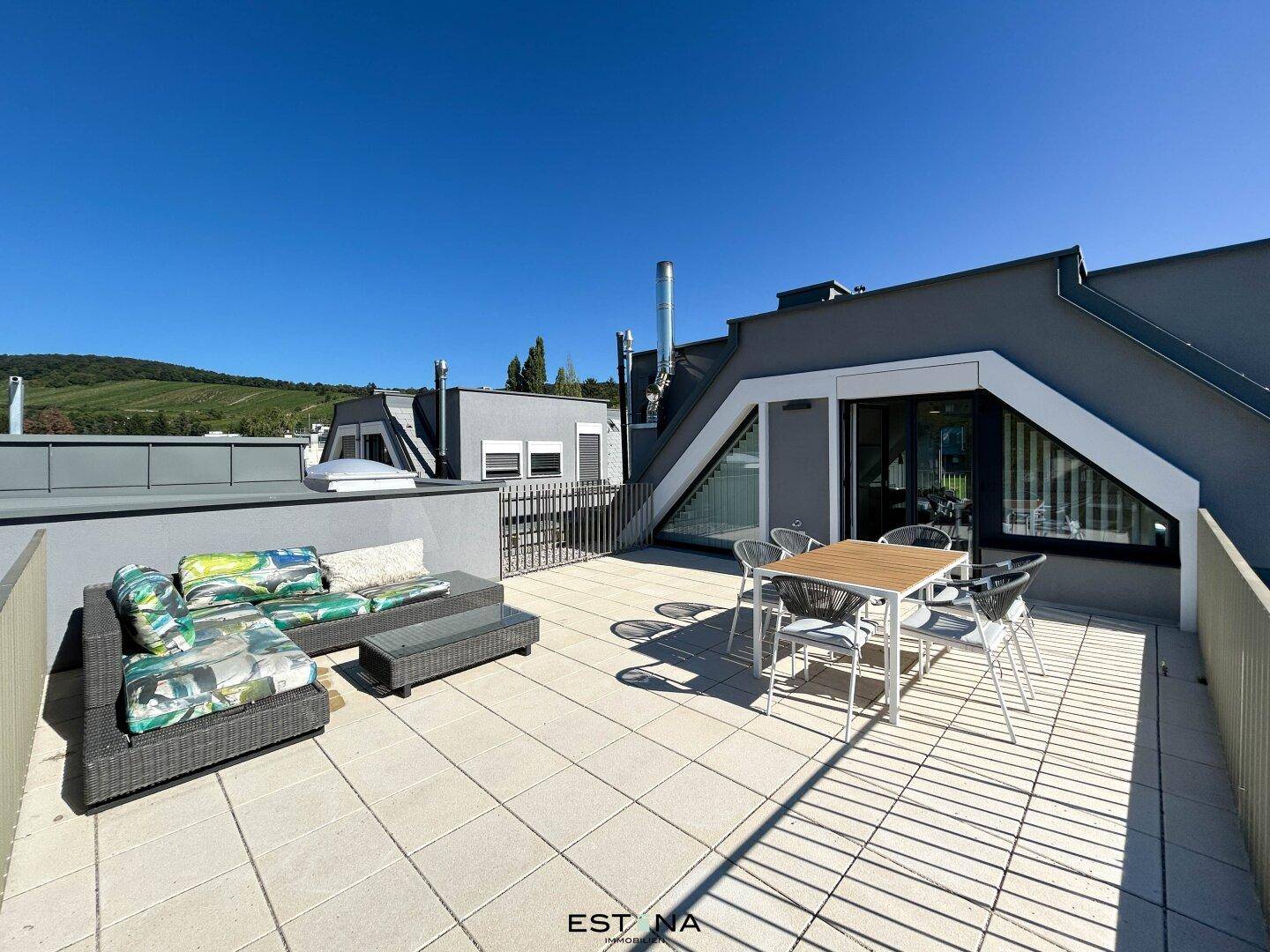 Geräumige Dachterrasse mit Lounge-Möbeln und Esstisch, umgeben von moderner Architektur.