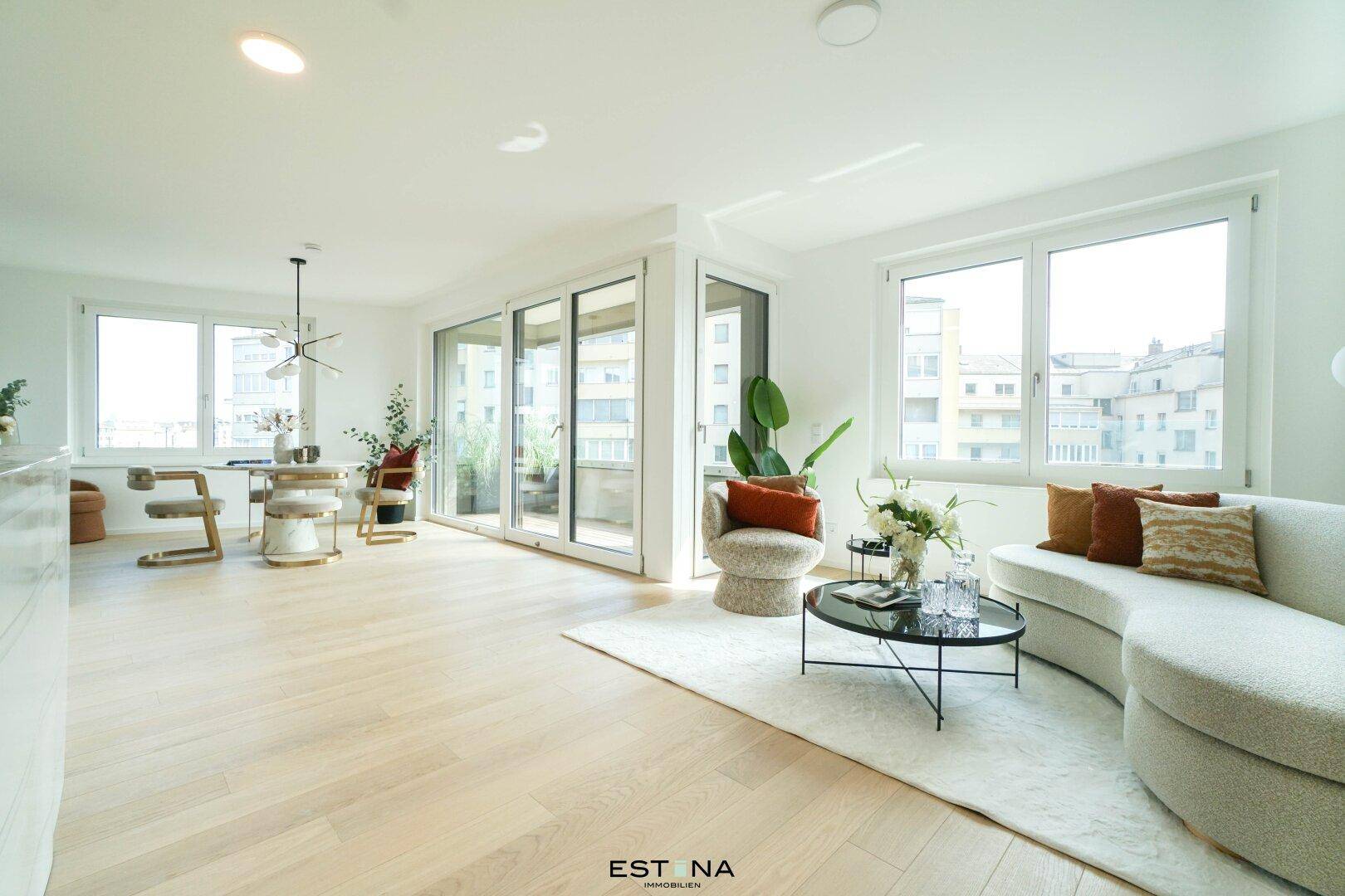 Heller, offener Wohn-Essbereich mit modernem Design, Parkettboden und Zugang zu einem Balkon.