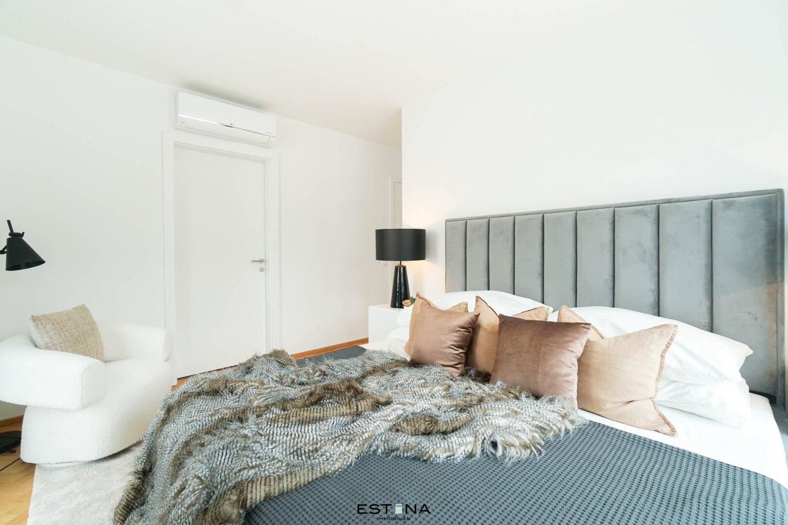 Modernes Schlafzimmer mit großem Bett, gepolstertem Kopfteil und Klimaanlage.