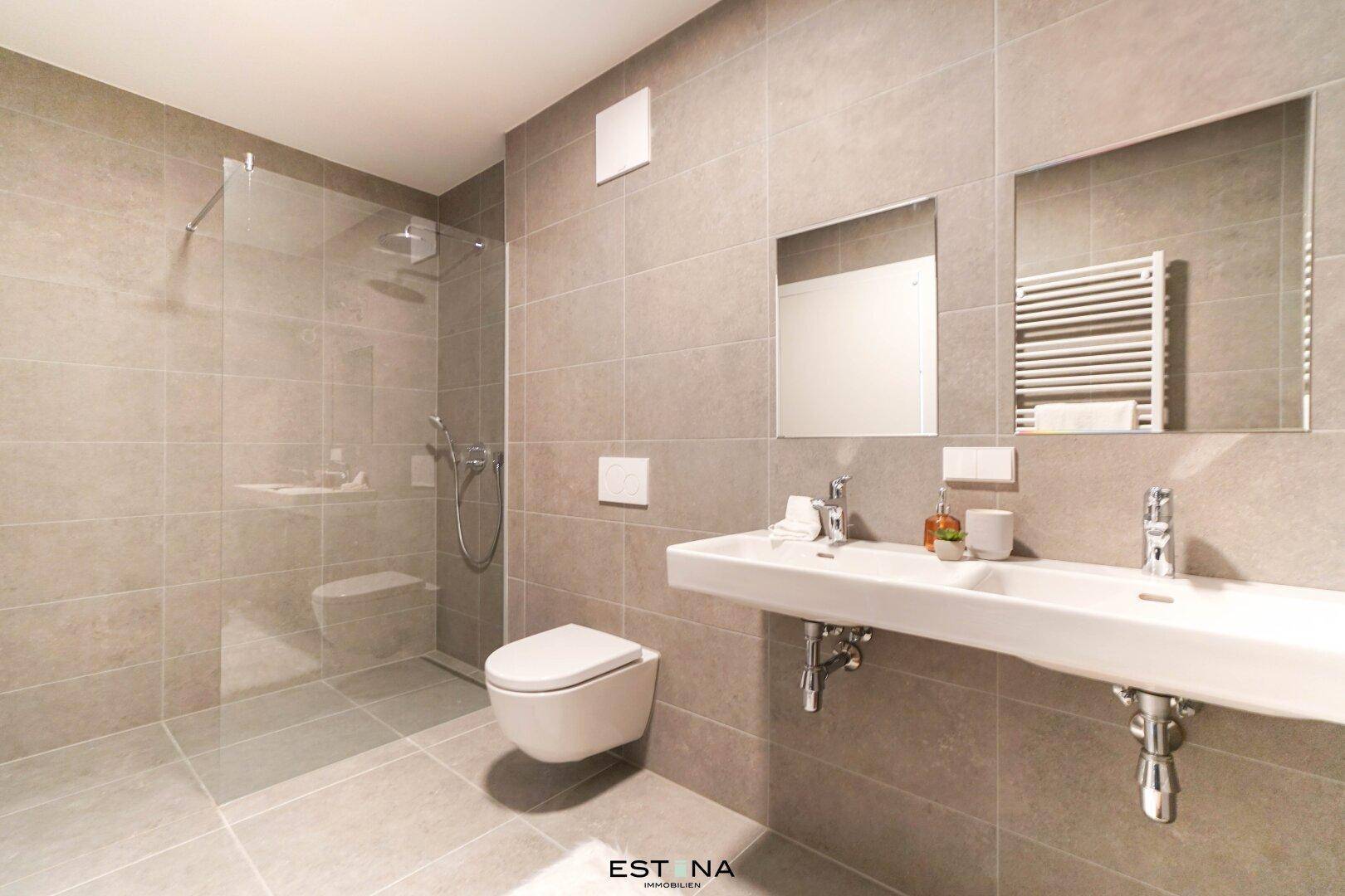 Modernes Badezimmer mit ebenerdiger Dusche, Doppelwaschbecken und Wand-WC.