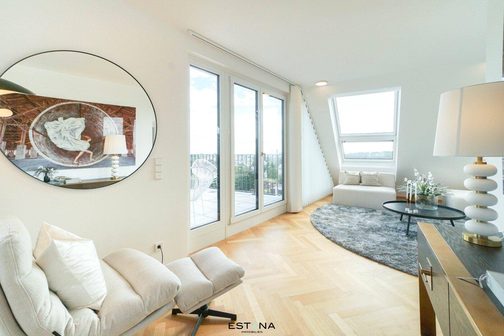 Heller Wohnbereich mit Lounge-Sessel, großem Spiegel und Zugang zu einem Balkon mit Aussicht.