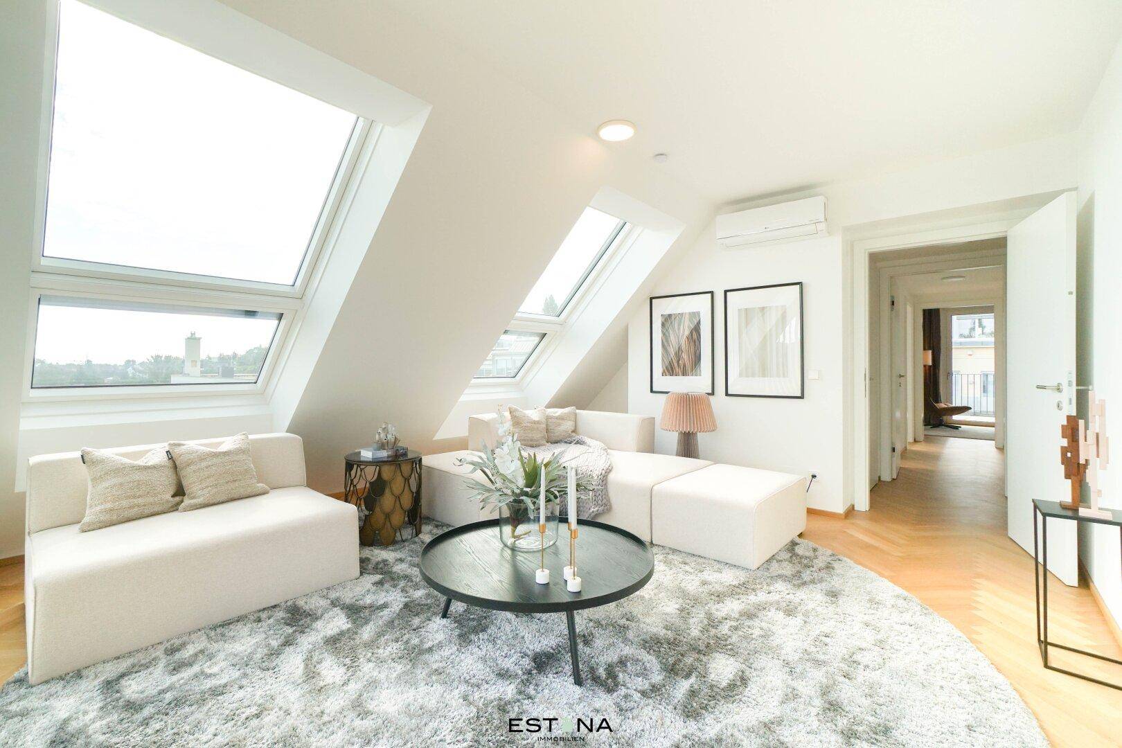 Gemütlicher Wohnbereich mit Sofa, Teppich und viel Tageslicht durch die Dachfenster.