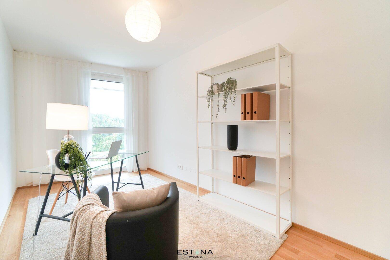 Helles Arbeitszimmer mit Schreibtisch, Regal und großem Fenster.