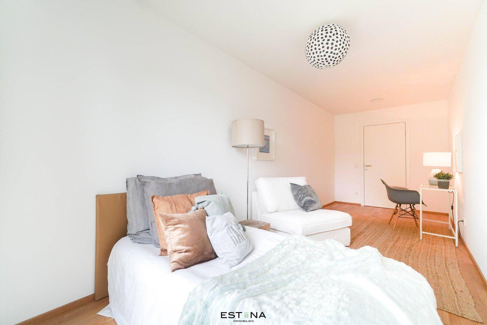Helles Schlafzimmer mit Einzelbett, Schreibtisch und modernem Deckenlicht.