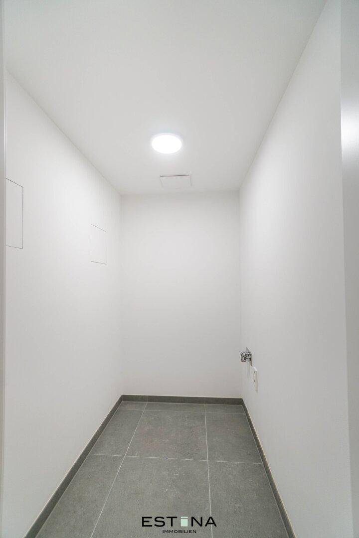 Schmaler Hauswirtschaftsraum mit Fliesenboden und Anschlussmöglichkeiten.