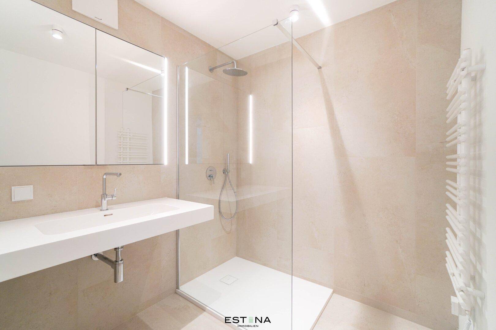 Elegantes Badezimmer mit begehbarer Dusche, modernem Waschbecken und großem Spiegel.