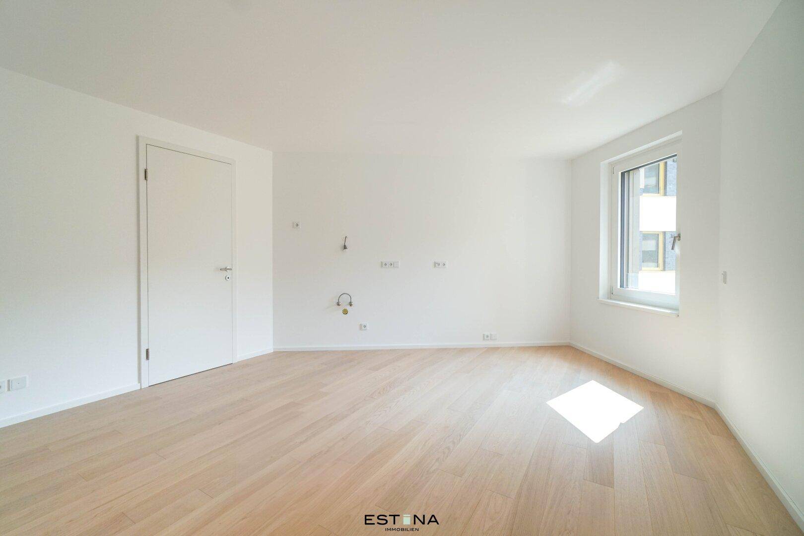 Lichtdurchfluteter Raum mit hellem Holzfußboden und einem Fenster, das viel Tageslicht hereinlässt.