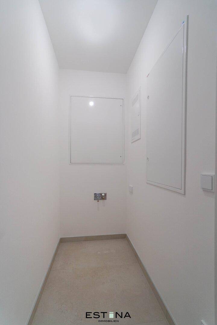Schmaler Hauswirtschaftsraum mit Fliesenboden und weißen Wänden, ausgestattet mit Revisionsklappen.