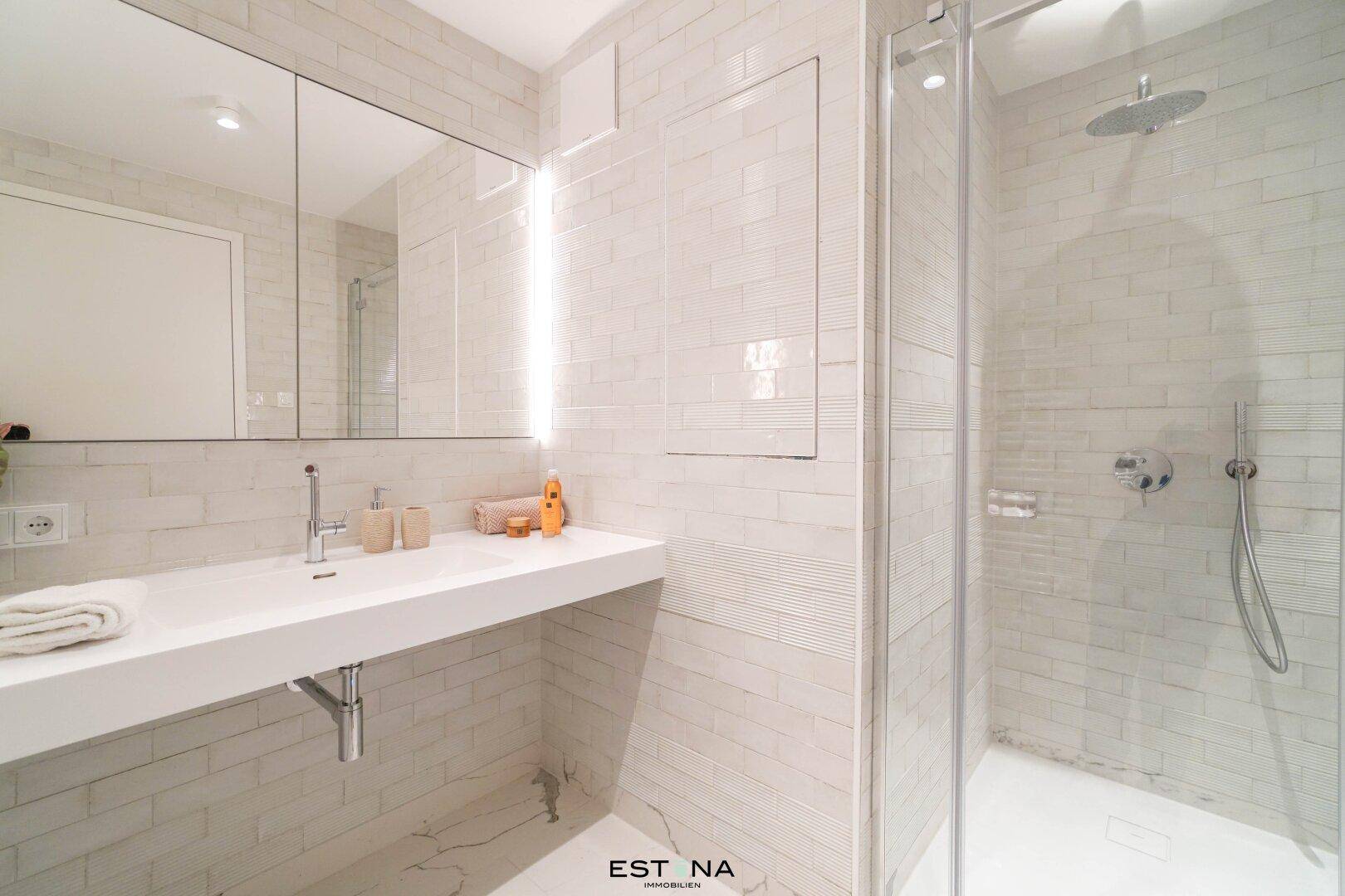 Helles Badezimmer mit begehbarer Dusche, modernem Waschtisch und großen Fliesen.