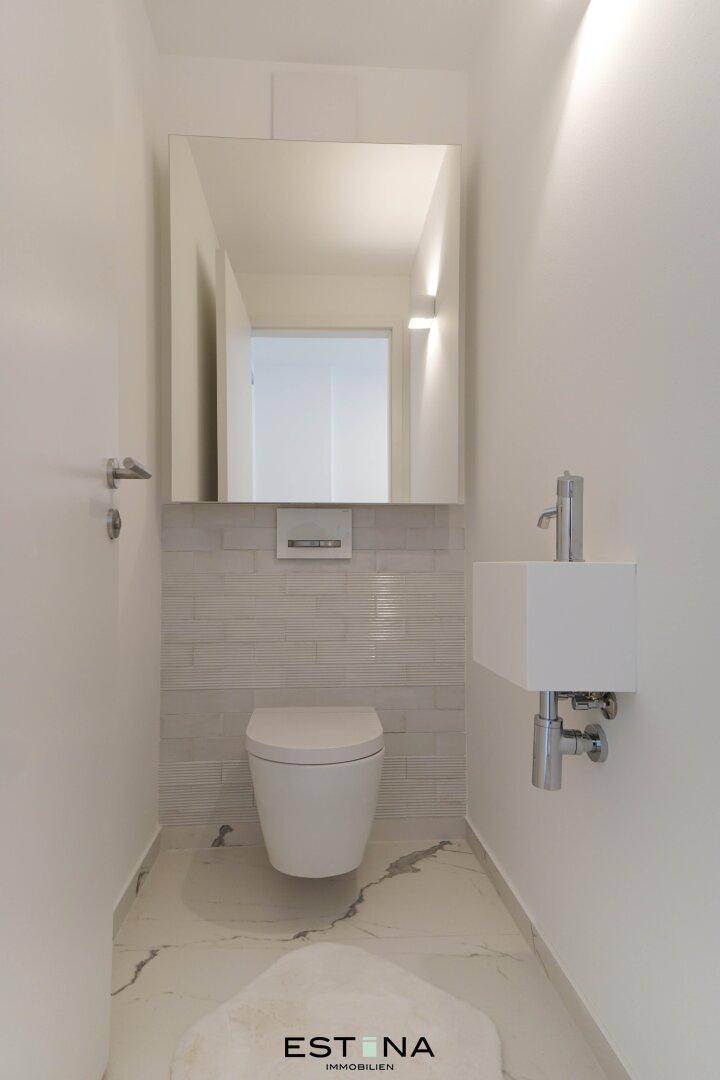 Modernes Gäste-WC mit wandhängender Toilette und kleinem Waschbecken.