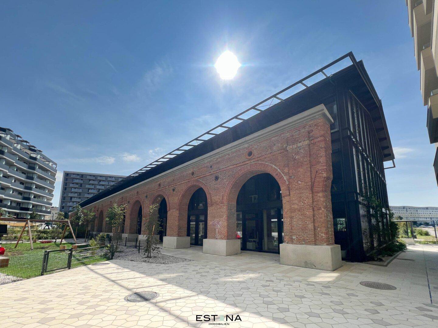 Historisches Backsteingebäude mit modernen Anbauten und einem Spielplatz im Vordergrund.