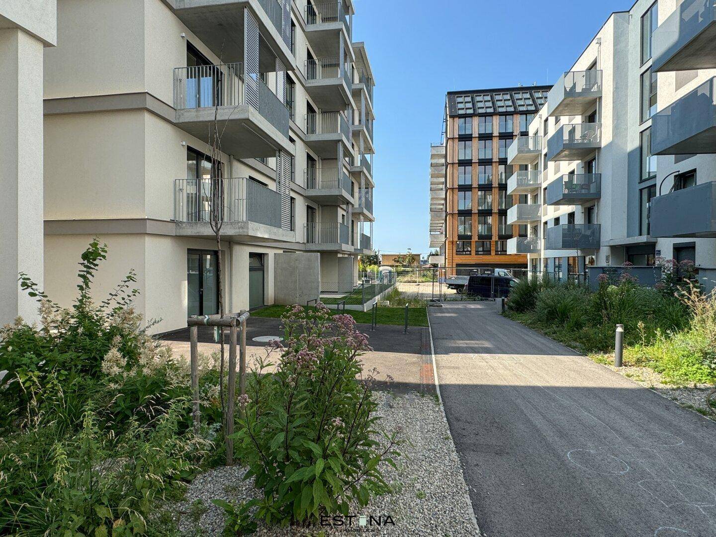 Moderne Wohngebäude mit Balkonen und gepflegten Grünflächen in einer sonnigen Umgebung.