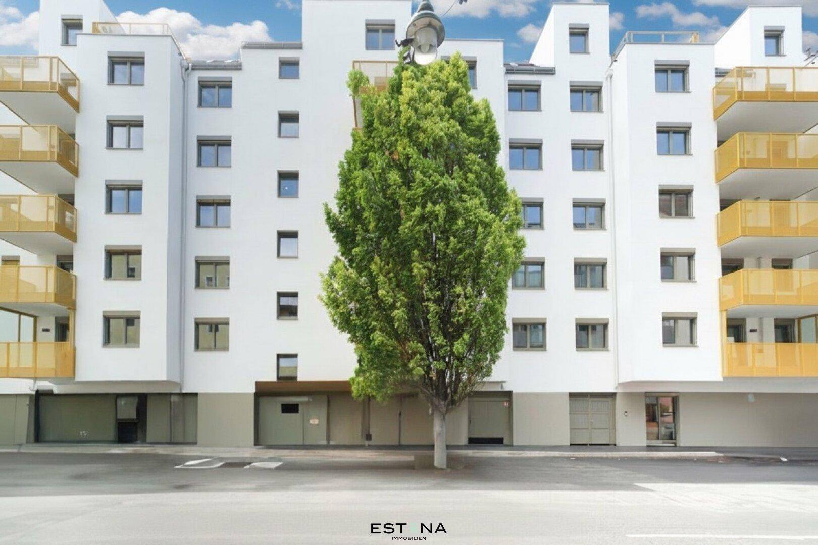 Moderne Fassade eines Wohngebäudes mit gelben Balkonen und einem hohen Baum davor.