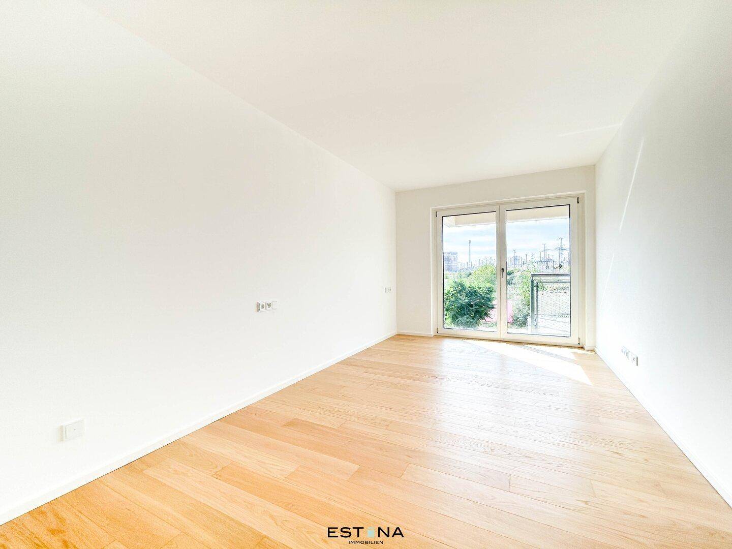 Helles Schlafzimmer mit Parkettboden und Zugang zu einem kleinen Balkon, ideal für frische Luft.