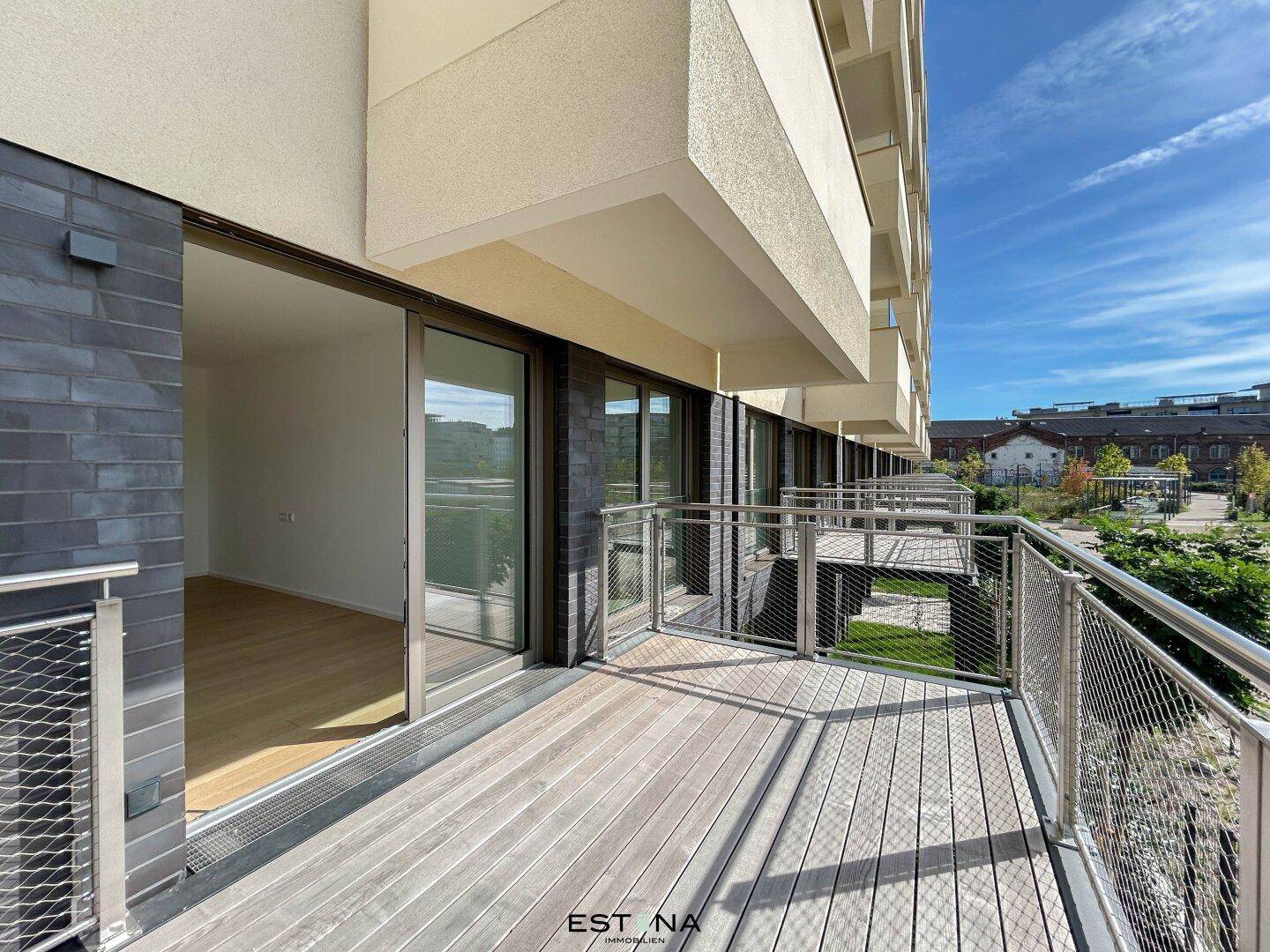 Geräumiger Balkon mit Holzboden und moderner Metallbrüstung, bietet einen schönen Ausblick ins Grüne.