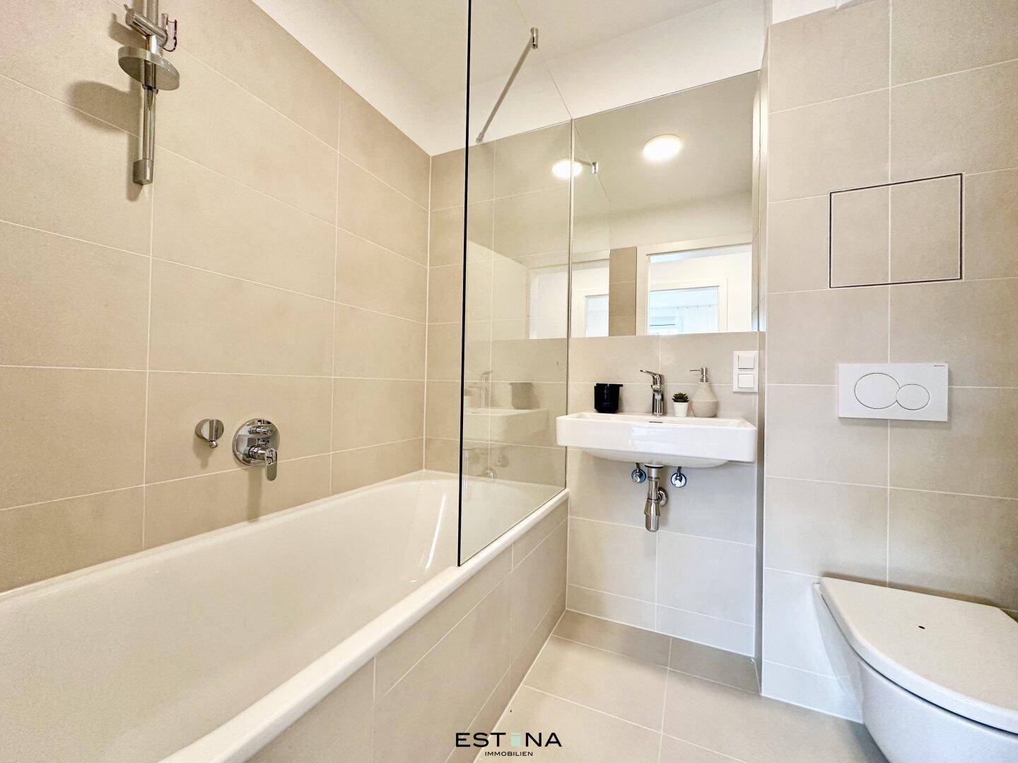 Modernes Badezimmer mit Badewanne, Wand-WC und beigefarbenen Fliesen.