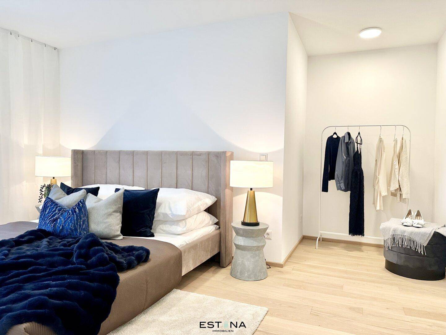 Gemütliches Schlafzimmer mit hellem Holzboden und modernem, gepolstertem Bett.