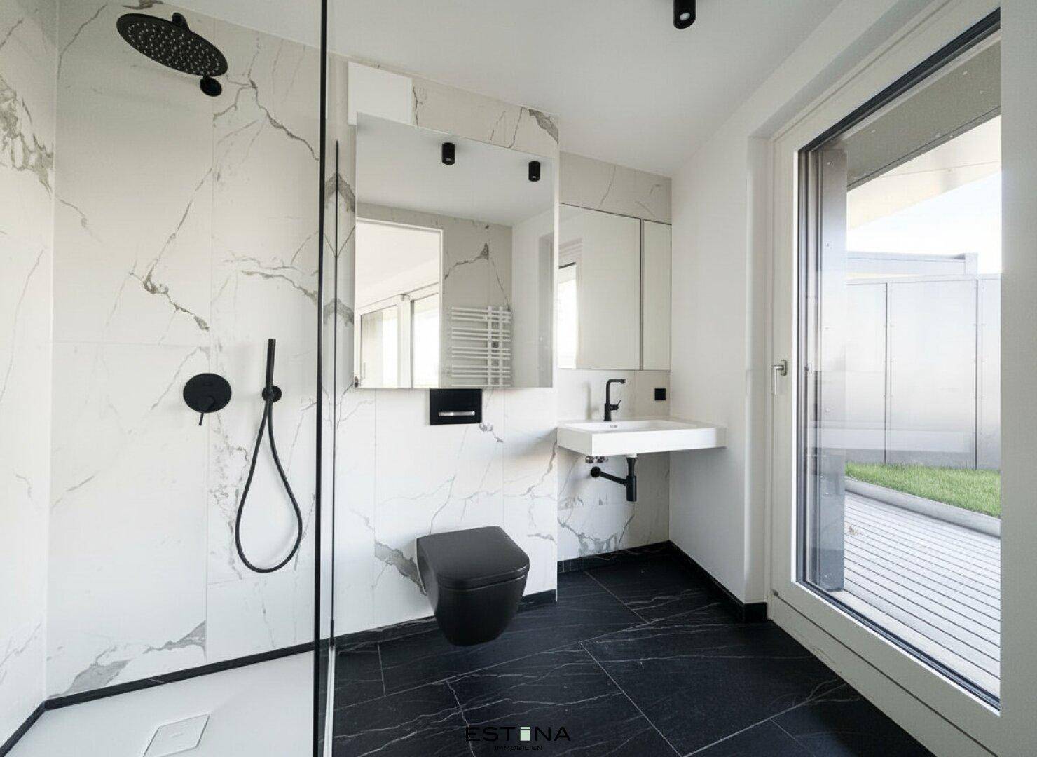Modernes Badezimmer mit schwarz-weißem Marmor, ebenerdiger Dusche und schwarzer Armatur.
