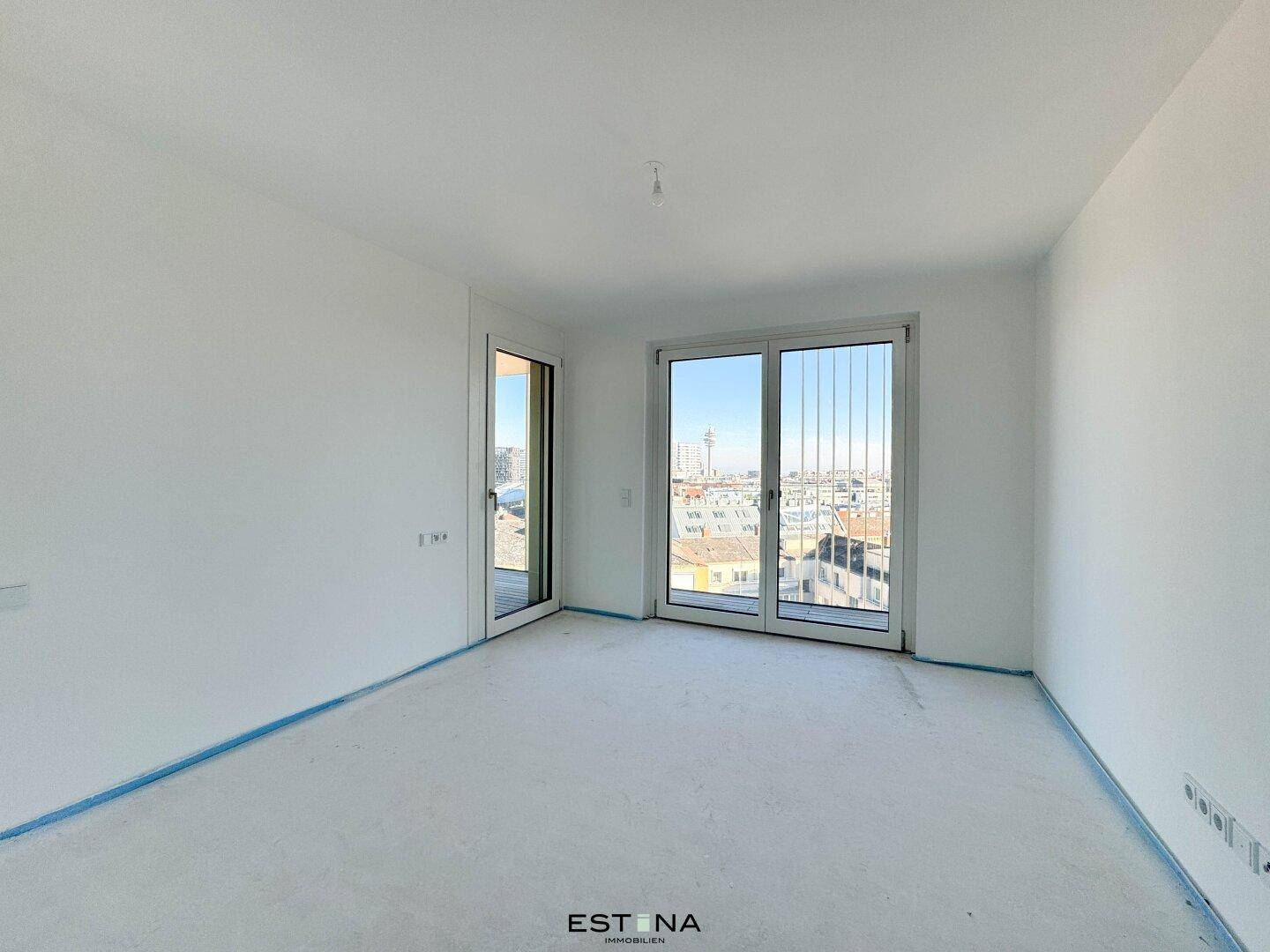 Unmöbliertes Zimmer mit großen Fenstern, die einen weiten Blick auf die Stadt ermöglichen.