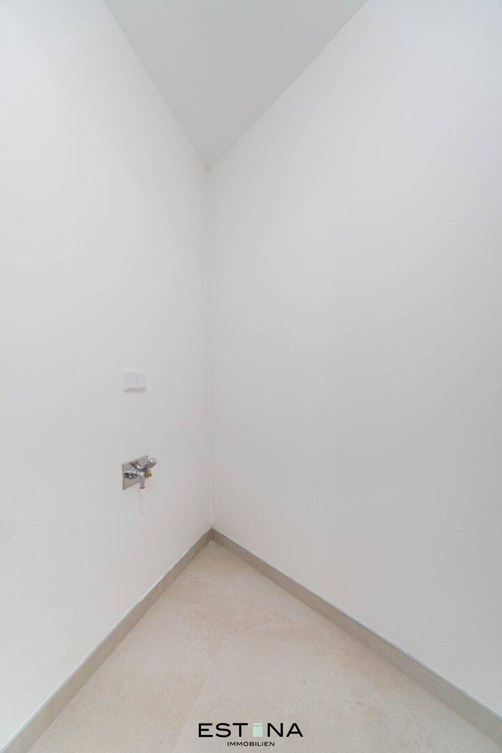 Kleiner, leerer Raum mit Fliesenboden und Anschlüssen, ideal als Abstellraum oder Hauswirtschaftsraum.