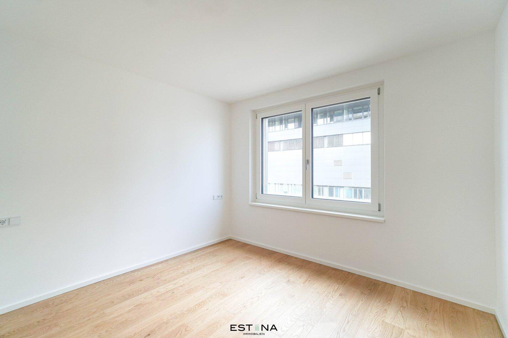 Helles, unmöbliertes Zimmer mit weiß gestrichenen Wänden und Parkettboden.