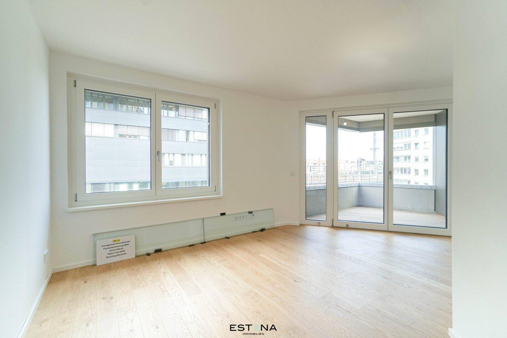Lichtdurchfluteter Wohnraum mit großen Fenstern und direktem Zugang zum Balkon.