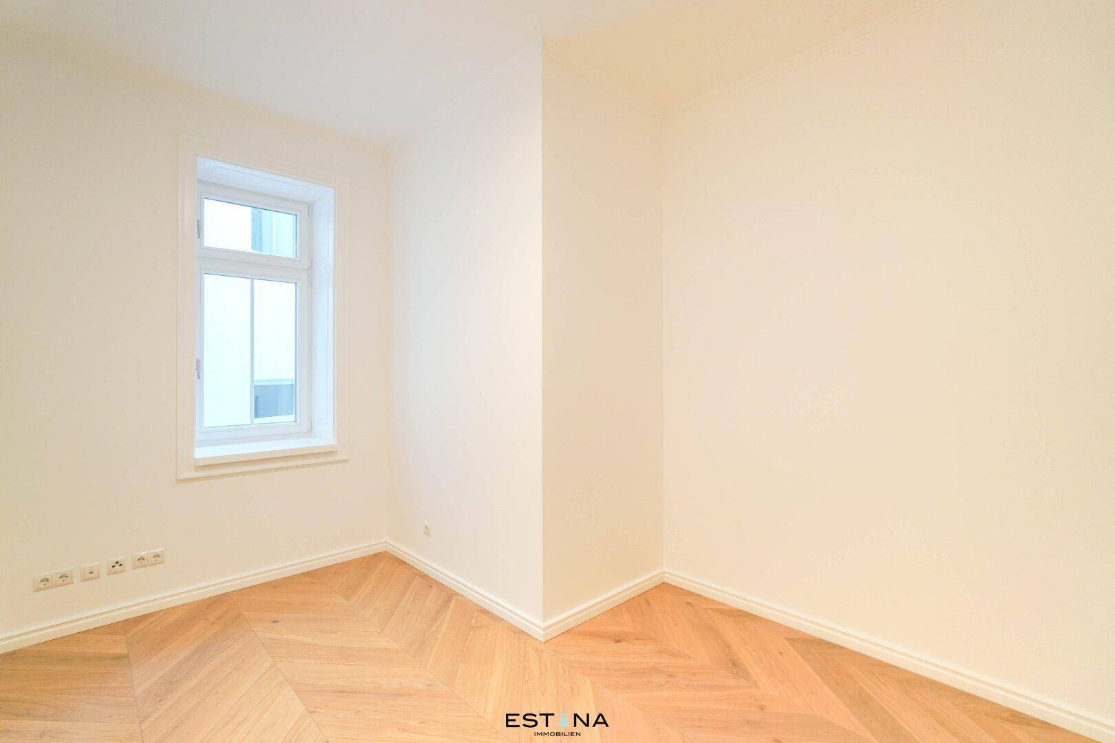 Gemütliches Zimmer mit hellem Fischgrätparkett und einem Fenster, perfekt als Schlaf- oder Arbeitszimmer.