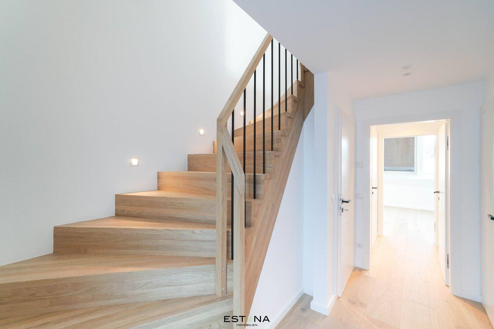 Moderne Holztreppe mit schwarzem Geländer und integrierter Beleuchtung.