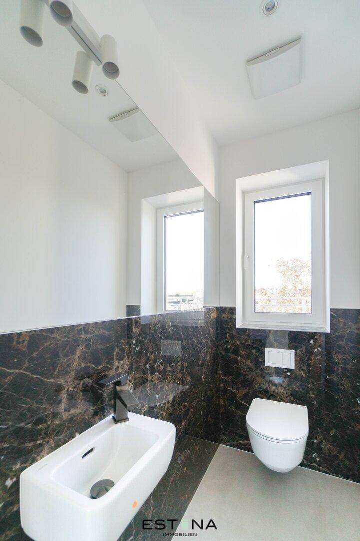 Modernes WC mit Bidet, wandhängender Toilette und Marmorfliesen.