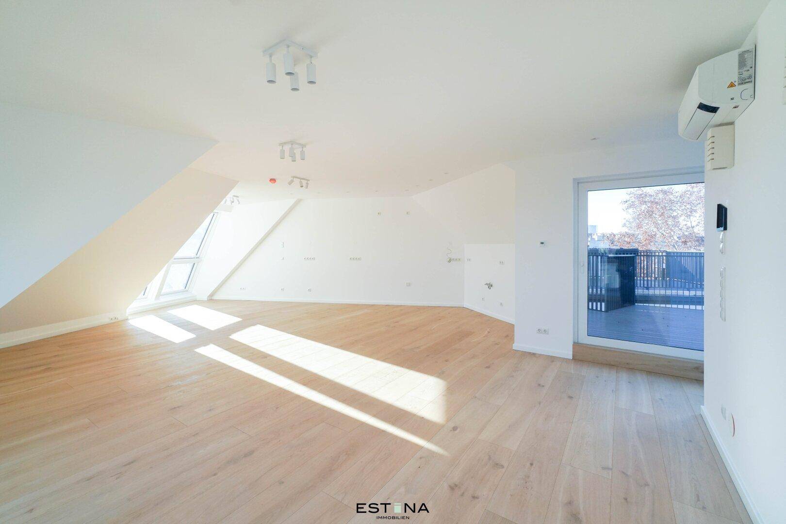 Geräumiger Dachgeschossraum mit Holzboden, Klimaanlage und Zugang zur Terrasse.