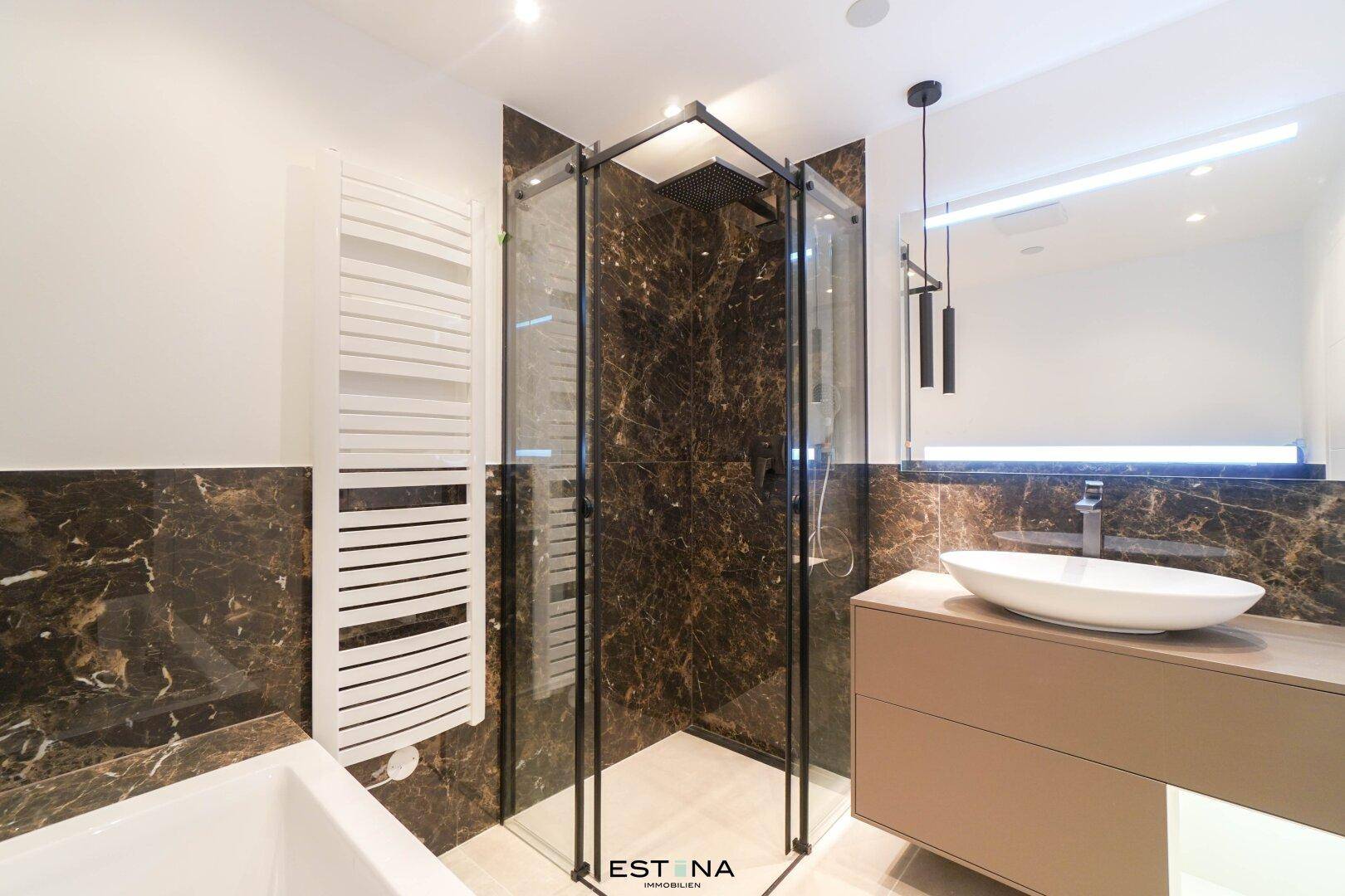 Modernes Badezimmer mit dunklen Marmorfliesen, Dusche und Handtuchheizkörper.