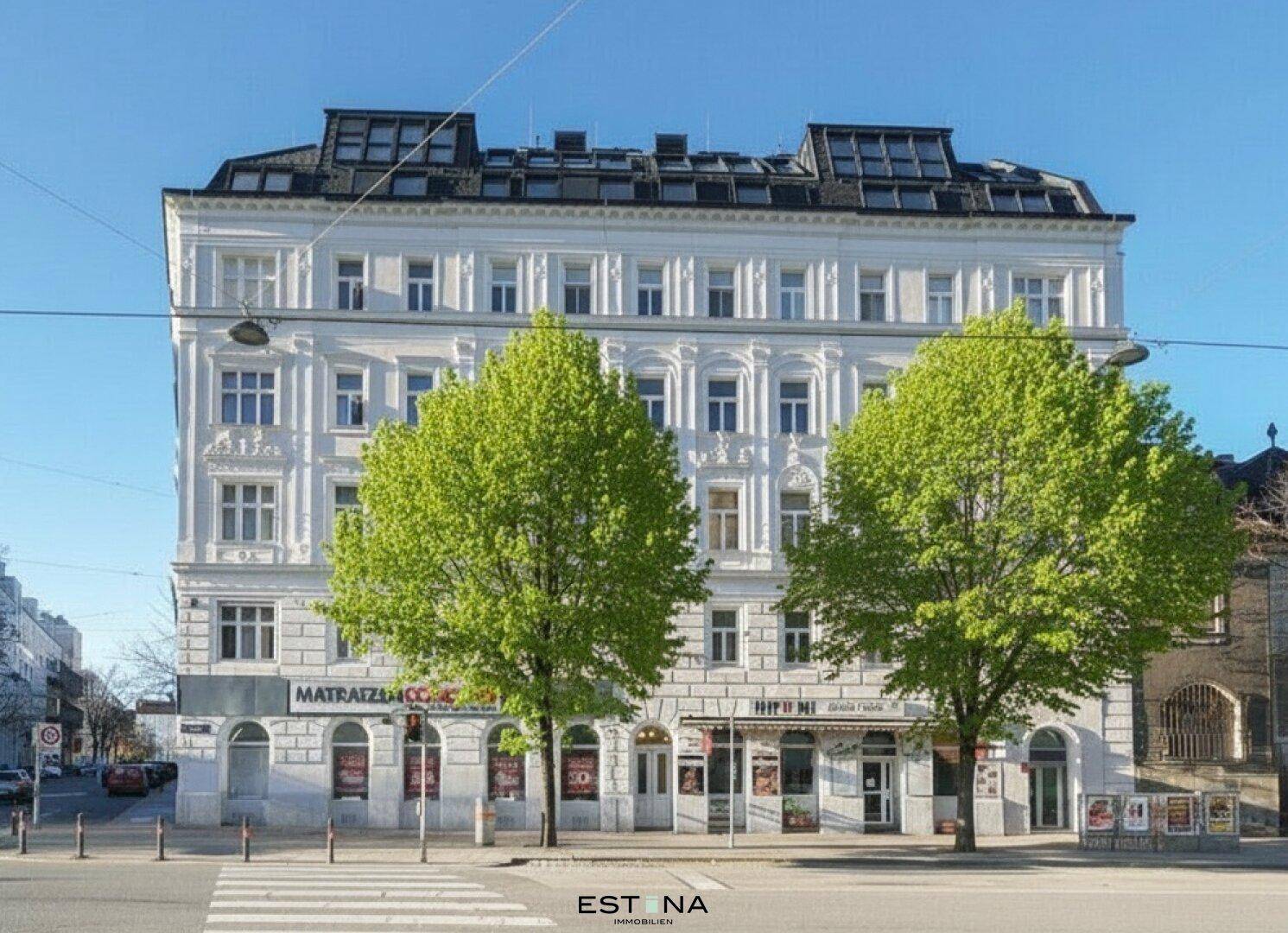 Klassische Fassade eines Altbaus mit neuem Dachgeschoss und Geschäften im Erdgeschoss.
