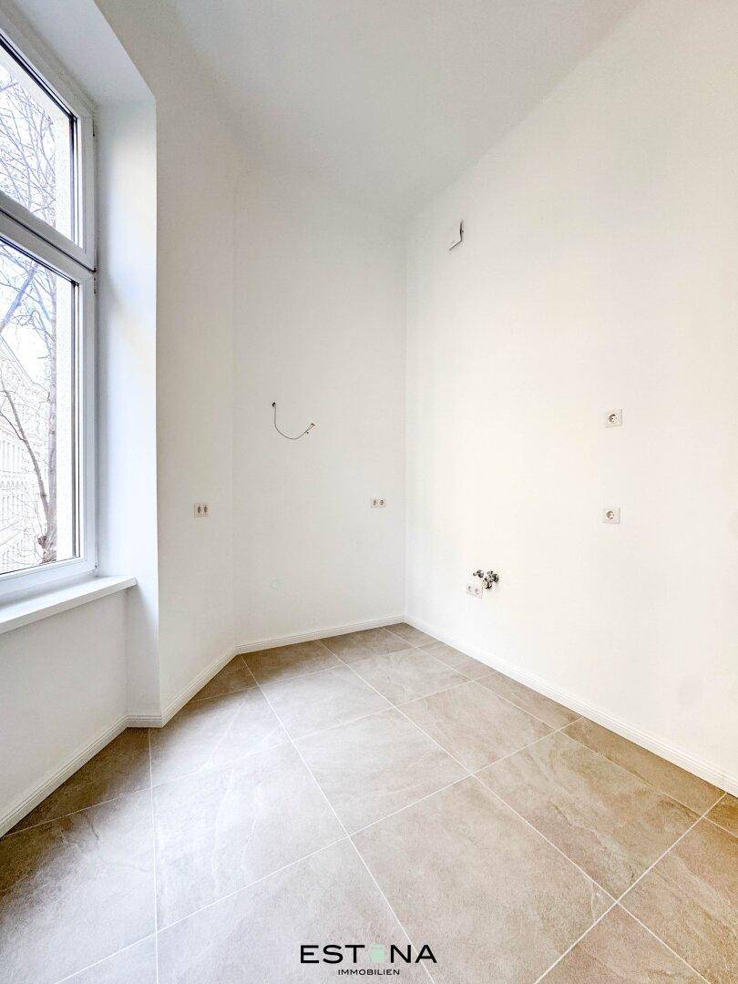 Heller Raum mit Fliesenboden und Fenster, vorbereitet für die Installation einer Küche, ideal für individuelle Gestaltung.